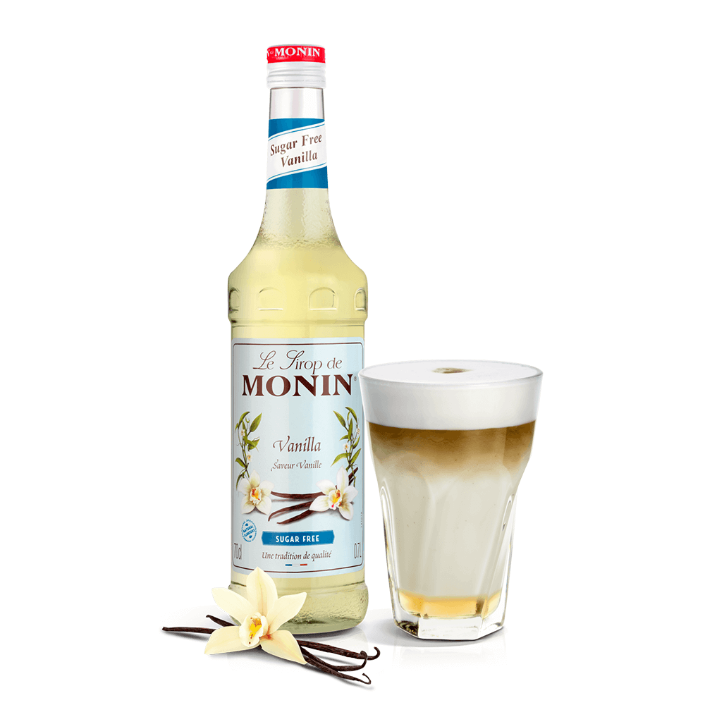 bottle of monin vanilla syrup beside a coffee in a glass