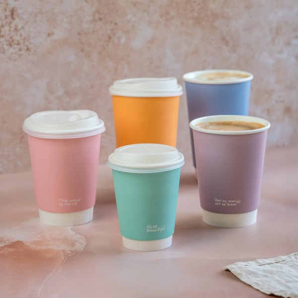 Five colorful paper cups with lids on a textured surface