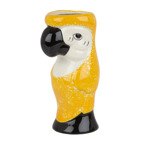 A ceramic tiki mug designed to resemble a parrot, with yellow body and black and white details on a white background.