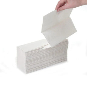 Hand pulling a white paper towel from a box on a white background