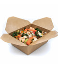 Cardboard takeout container with a meal of shrimp, vegetables, and greens on a white background