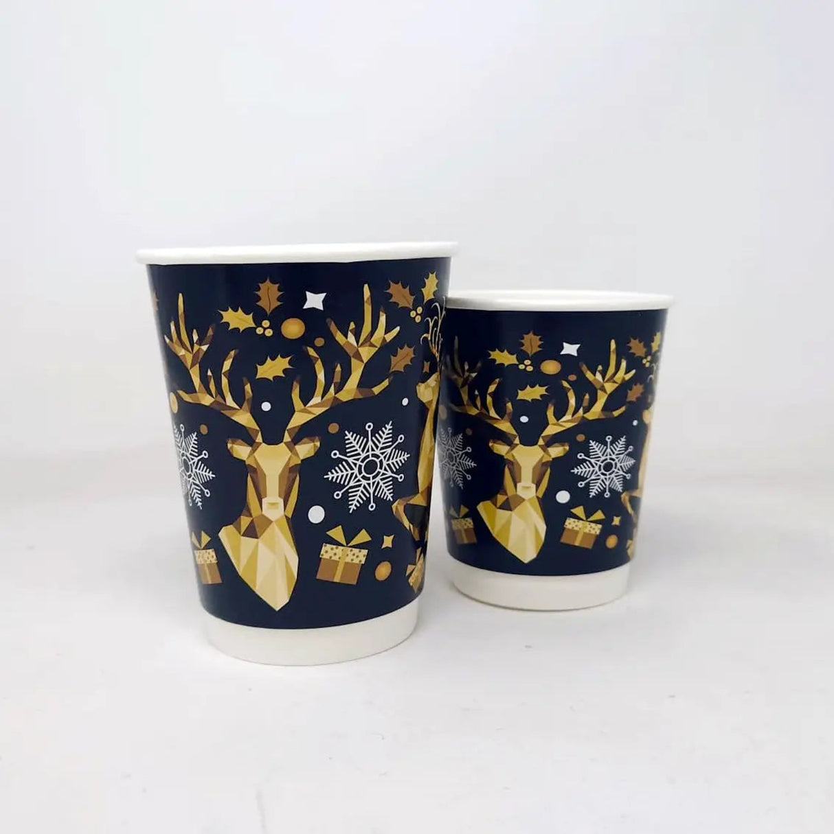 Two paper cups with deer and snowflake design on a white background