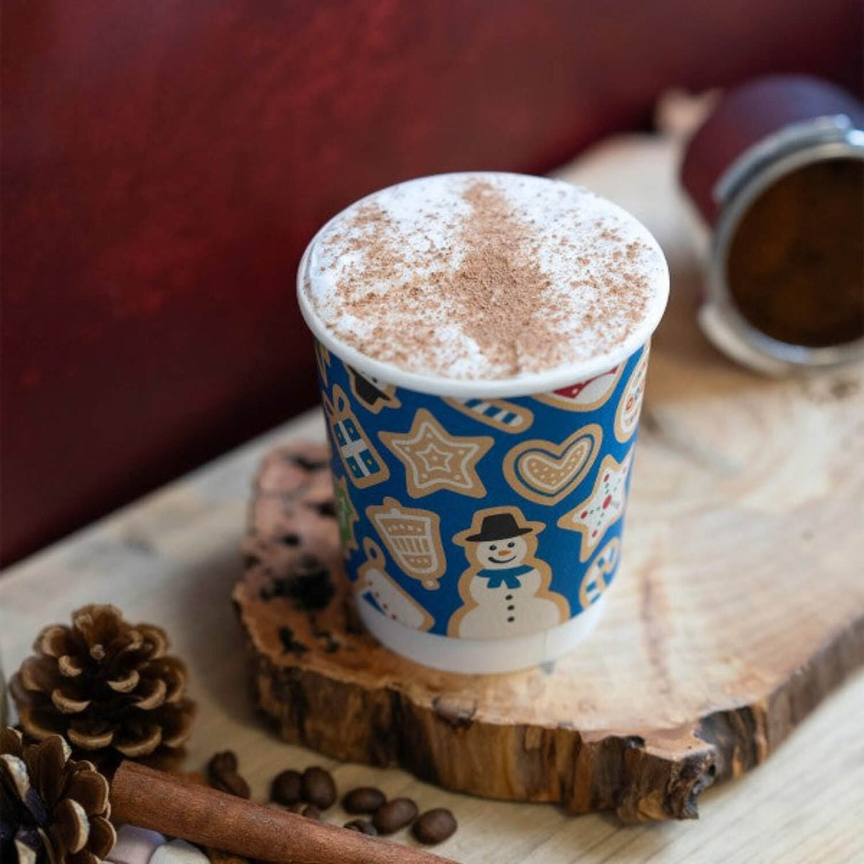 Hot chocolate in a blue cup with gingerbread men design on a wooden surface.
