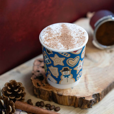Hot chocolate in a blue cup with gingerbread men design on a wooden surface.