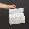 Hand holding a stack of white paper towels against a black background