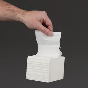 Hand picking a white napkin from a stack against a black background