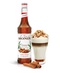 monin cinnamon syrup bottle beside a creamy drink in a glass