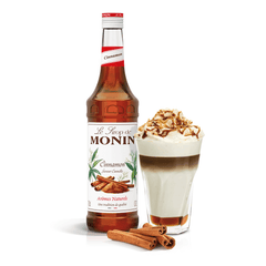 monin cinnamon syrup bottle beside a creamy drink in a glass