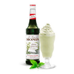 bottle of monin green tea syrup beside a long creamy drink