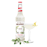 monin jasmine syrup bottle beside a cocktail glass 