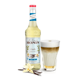 bottle of monin vanilla syrup beside a coffee in a glass