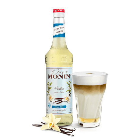 bottle of monin vanilla syrup beside a coffee in a glass