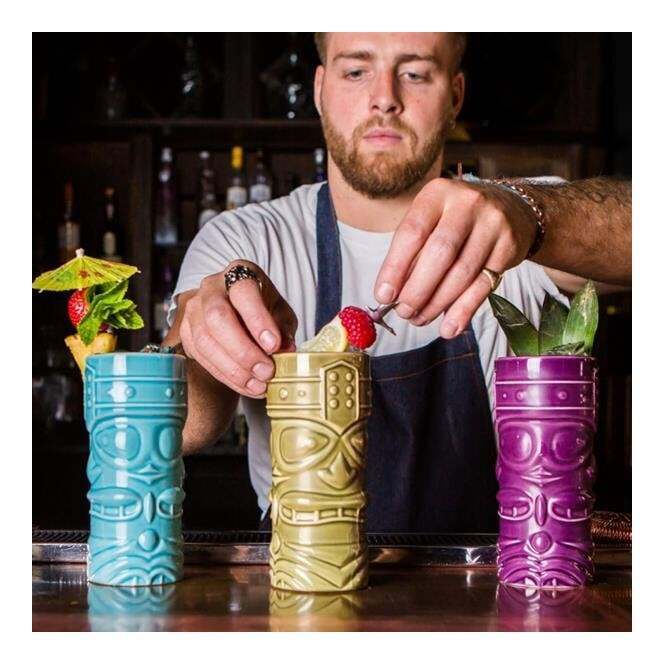 Barman serving drinks in multicoloured tiki mugs