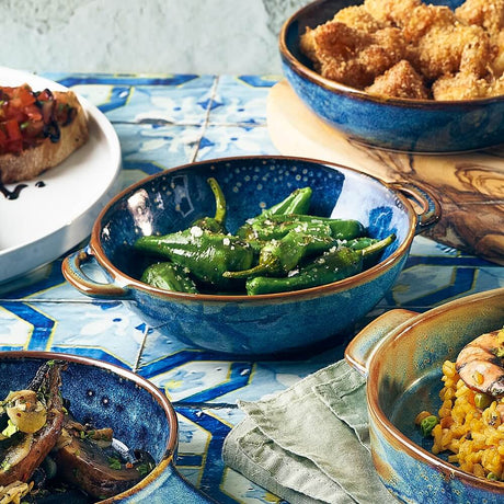 Assorted dishes including green beans in a blue bowl on a decorative tablecloth.