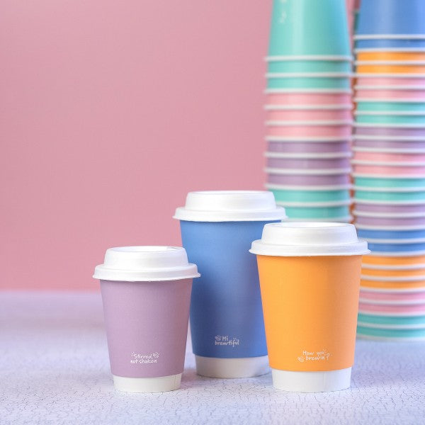 Colorful paper cups with lids on a pink background