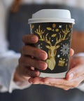 Person holding a festive coffee cup with reindeer and snowflake design.