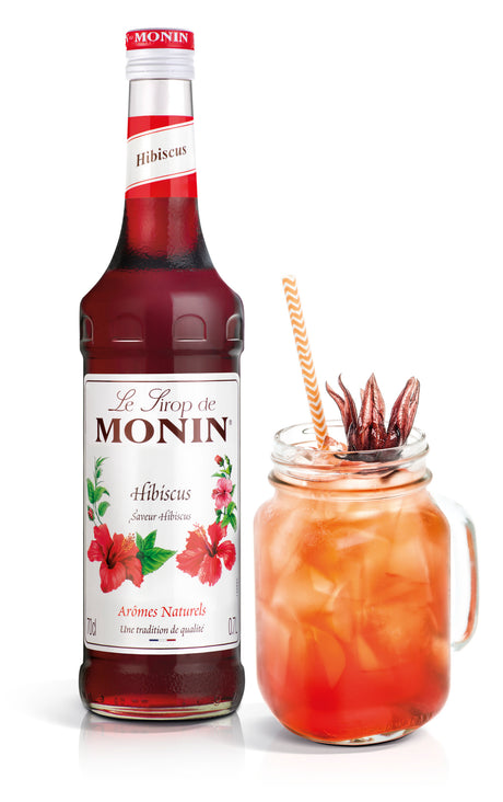 bottle of monin hibiscus syrup and a cocktail in a mason jar
